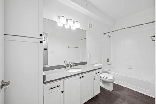 A white bathroom with a sink, mirror, toilet and bathtub.