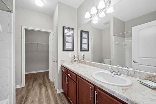 A bathroom with a sink, mirror, and wooden floors.