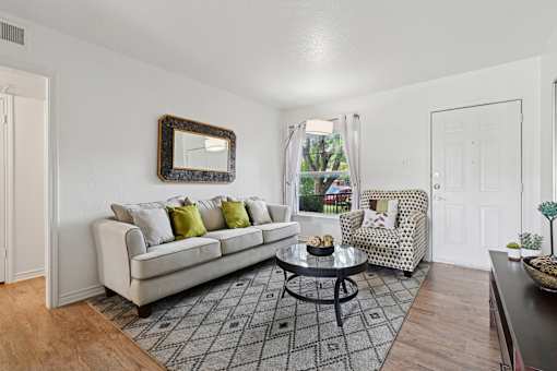 A living room with a white couch, a coffee table, and a chair with a patterned cushion.