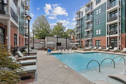 A pool area with a hot tub and lounge chairs.