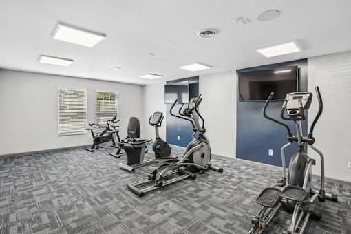 A gym with a variety of exercise equipment including treadmills, stationary bikes, and elliptical machines.