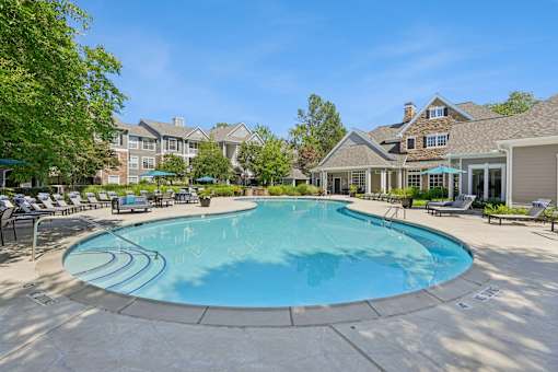 A large swimming pool surrounded by lounge chairs and umbrellas.
