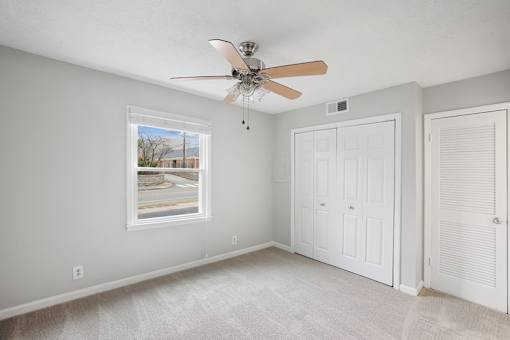A room with a ceiling fan and a window showing an outdoor view.