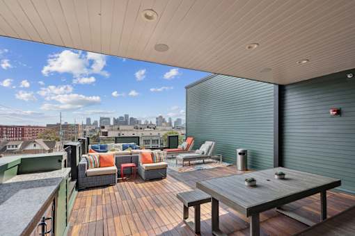 A wooden table is in the middle of a patio with a city skyline in the background.
