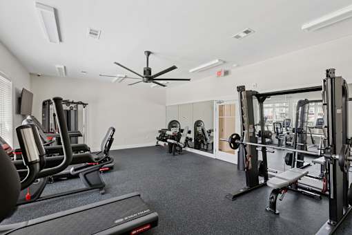 A spacious gym with a variety of equipment including treadmills, elliptical machines, and weight machines.