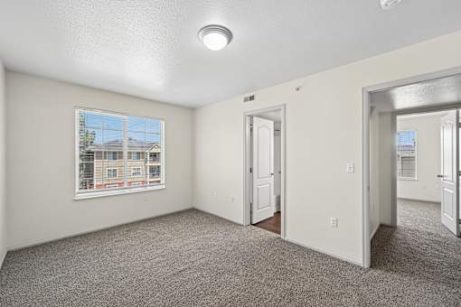 A room with a carpeted floor and a window showing a building outside.