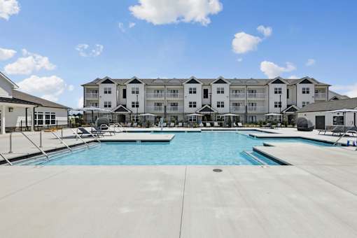 A large swimming pool in front of a multi-story apartment building.