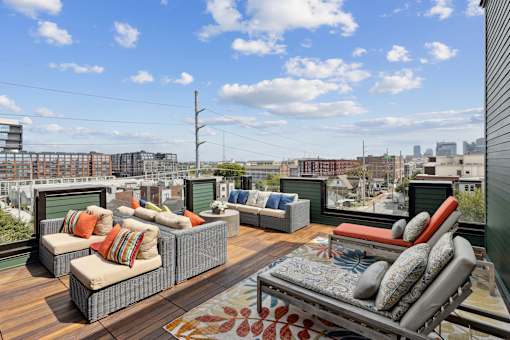 A patio with couches and a rug on a wooden deck.