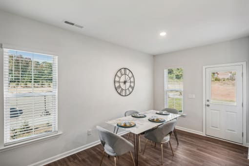 a dining room with a table and chairs and a clock on the wall