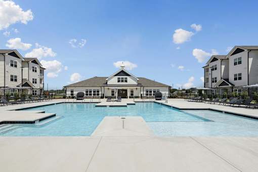 A large swimming pool in front of a building with a white roof.