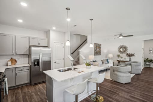 a kitchen and living room with a white counter top and a stainless steel refrigerator