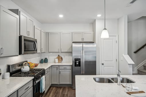 a white kitchen with stainless steel appliances and marble counter tops