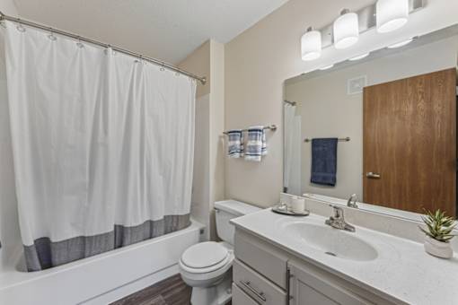 A bathroom with a white toilet, a white sink, and a white shower curtain.