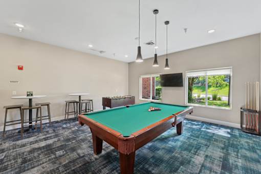 A pool table is in the middle of a room with a green cloth on it.