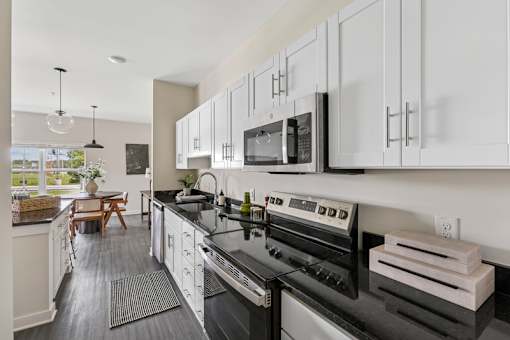 A modern kitchen with black countertops and white cabinets.