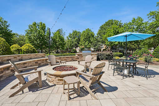 A patio with a fire pit and chairs.
