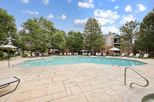 A pool surrounded by trees and chairs.