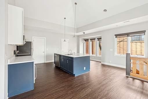 A kitchen with a blue island and wooden floors.