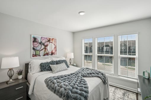 a bedroom with a bed and three windows