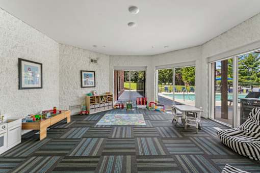 A room with a striped couch and a rug with a table and chairs.