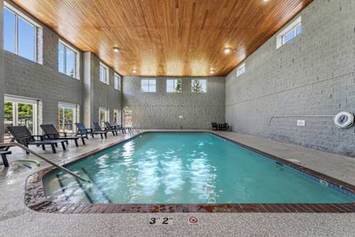 A large indoor swimming pool with a wooden ceiling and concrete walls.