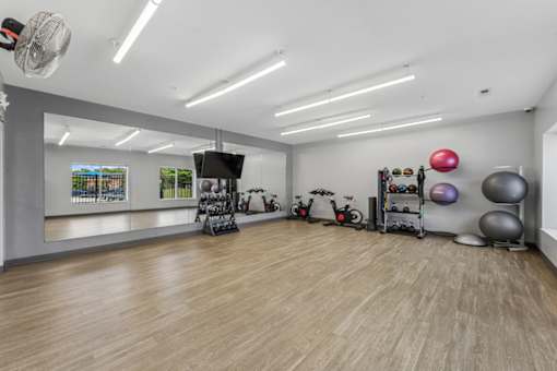 A gym with exercise equipment and a fan.