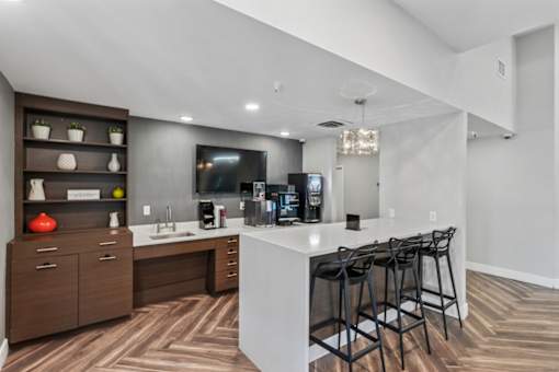 A modern kitchen with a white countertop and dark wood flooring.