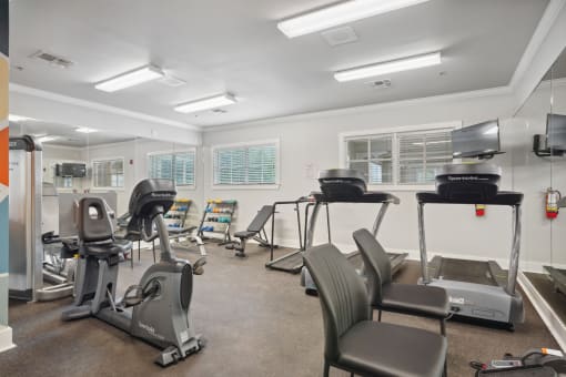a gym with treadmills and other exercise equipment and windows