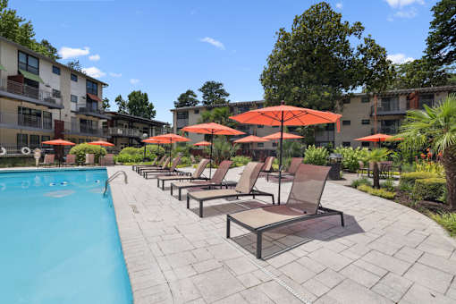 A pool surrounded by chairs and umbrellas.