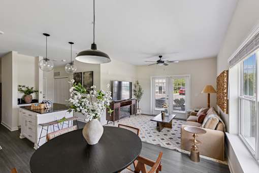 A modern kitchen with a black table and a ceiling fan in the living room.