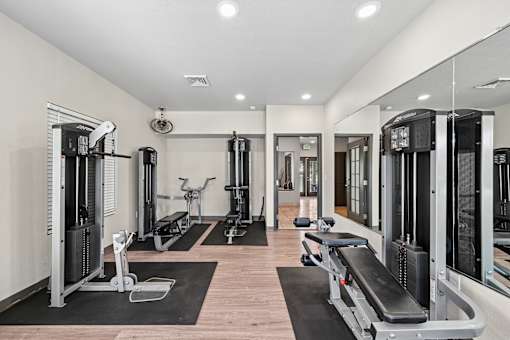 A gym with a variety of equipment including treadmills, weights, and exercise machines.