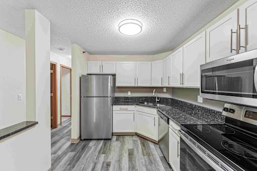 A kitchen with a stainless steel refrigerator, microwave, and oven.