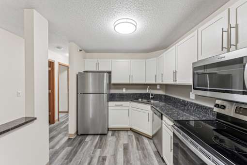 A kitchen with a stainless steel refrigerator, microwave, and oven.