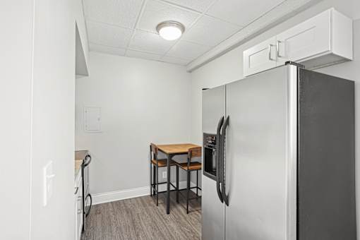 A kitchen area with a refrigerator, a table and chairs.