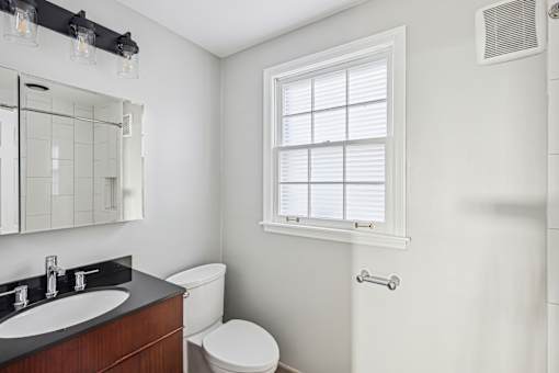 A bathroom with a toilet, sink, and window.