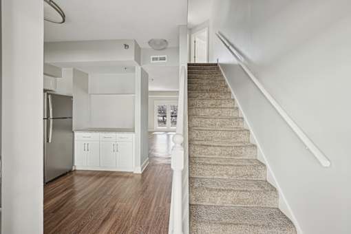 A staircase with a beige carpeted runner leads up to a white door.