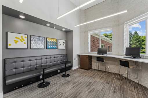 A room with a bench, chairs, and a desk with a laptop.