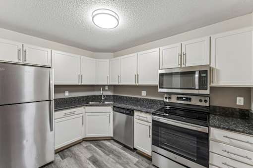 A kitchen with white cabinets and a stainless steel refrigerator.