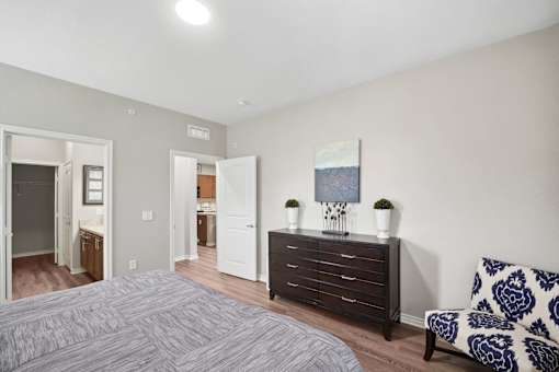 A bedroom with a bed, dresser, and chair.