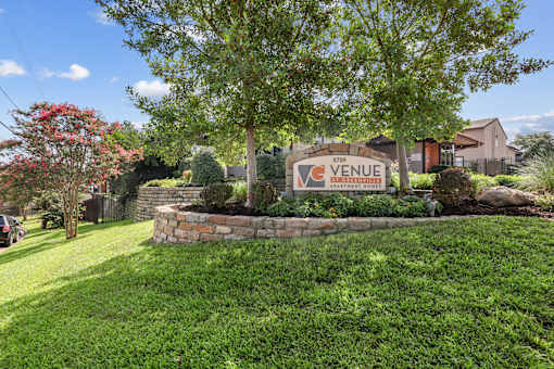 A sign that says "VENUE" is in front of a tree.