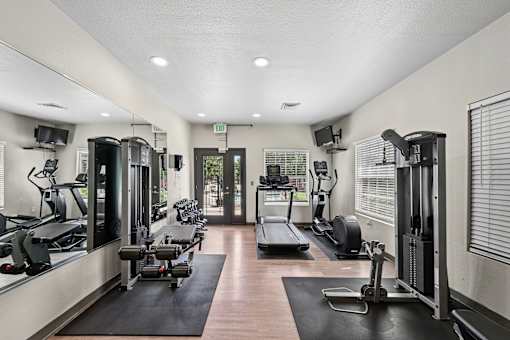 A gym with a variety of equipment including treadmills, weights, and exercise machines.