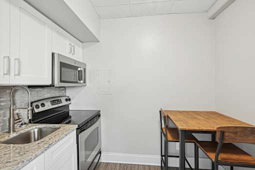 A kitchen with a sink, stove, oven, and microwave.