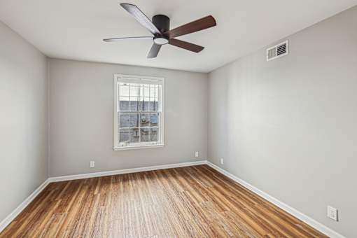 A room with a ceiling fan and wooden flooring.
