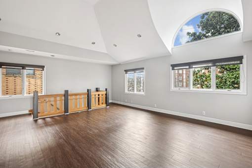 A room with wooden floors and a large arched window.