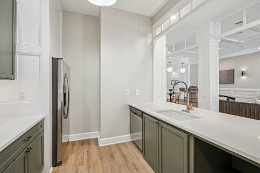 A kitchen with a refrigerator, sink, and cabinets.