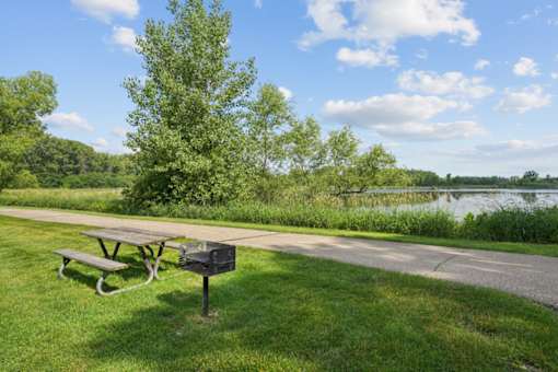 A picnic table sits on a grassy area next to a road with a mailbox in front of it.