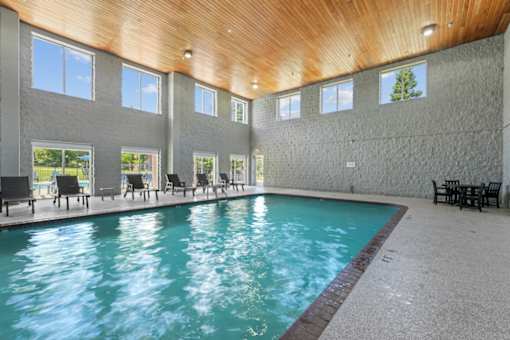 A large indoor swimming pool with a wooden ceiling and multiple windows.