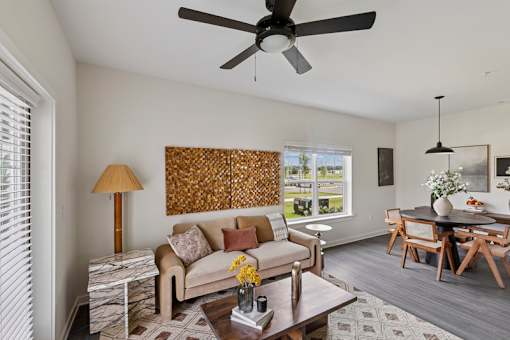 A living room with a couch, coffee table, and a ceiling fan.