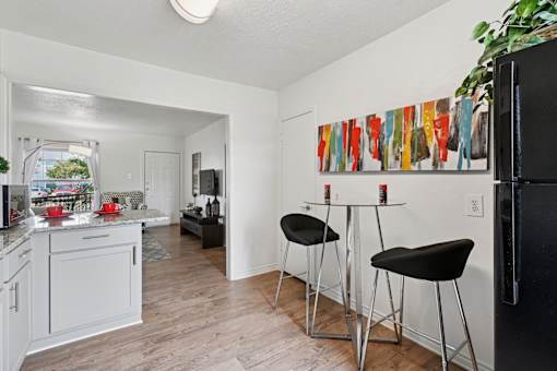 A kitchen with a bar stool and a fridge.
