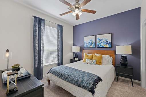 A bedroom with a bed, nightstand, and a ceiling fan.